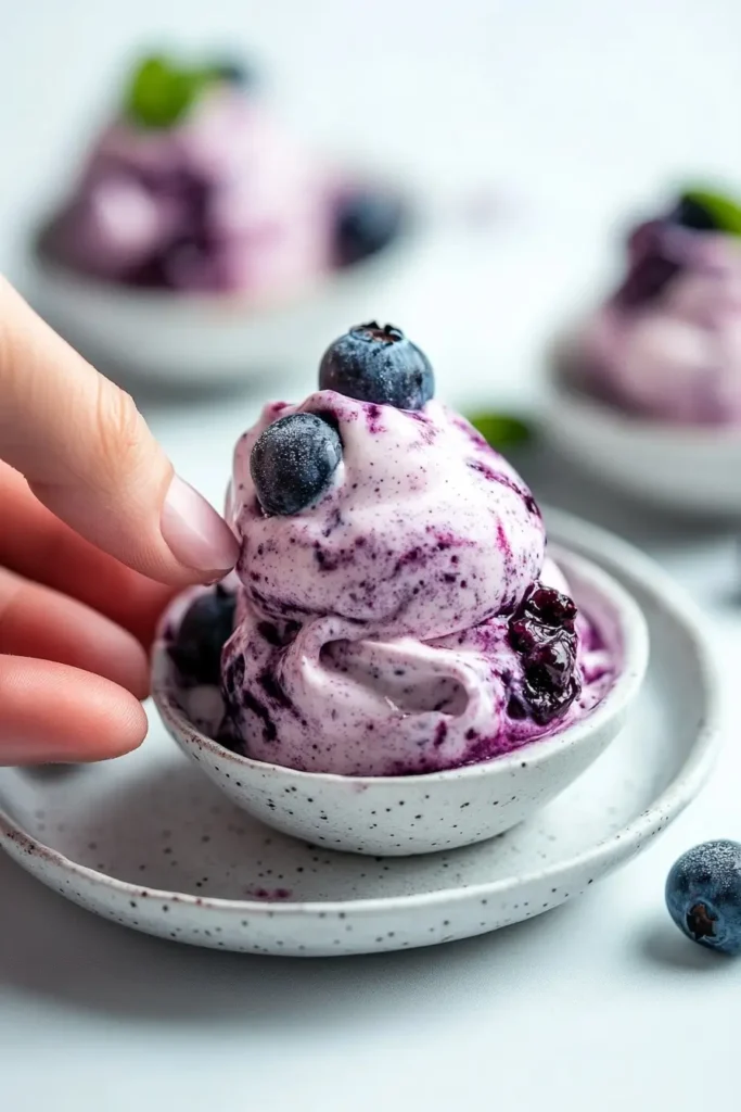 Someone enjoying a Blueberry Swirl Yogurt Bite with a blueberry swirl.