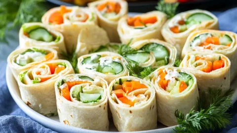 Fresh Vegetable Tortilla Roll Ups served on a plate with vibrant vegetables.